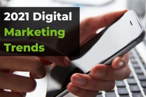 2021 Digital Marketing Trends in over a black background on top of a photo of a hand holding a smart phone