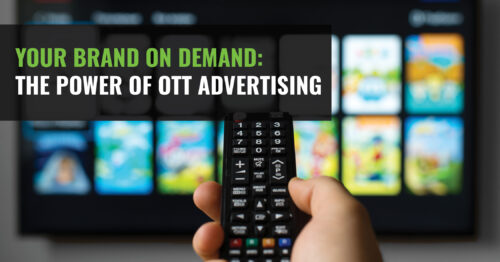 A hand holding a remote in front of a TV